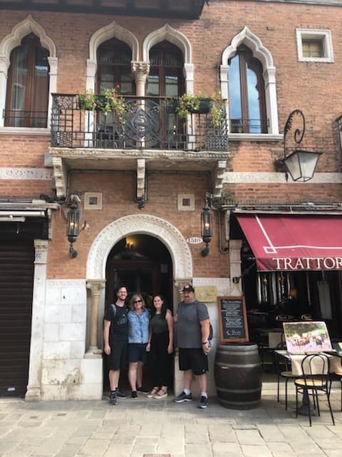 The Lombardo family posing next to the restaurant from their painting.