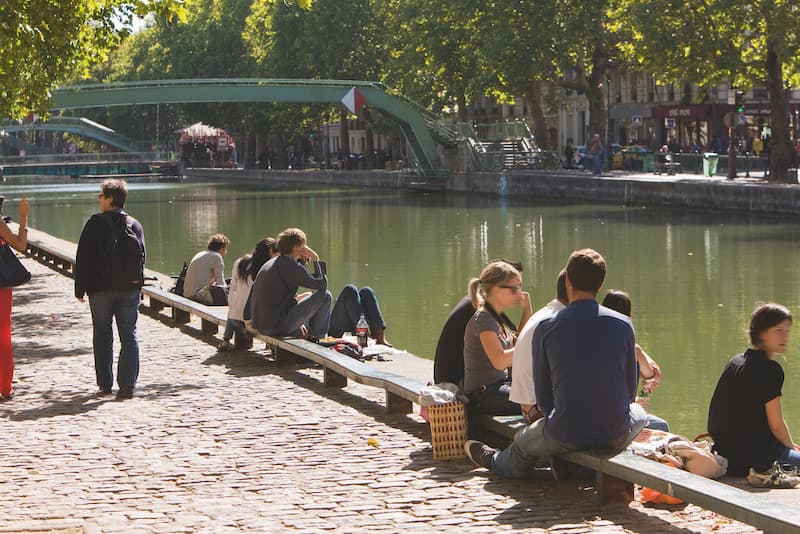 People sitting along the Canal Saint Martin in Paris on a sunny afternoon.