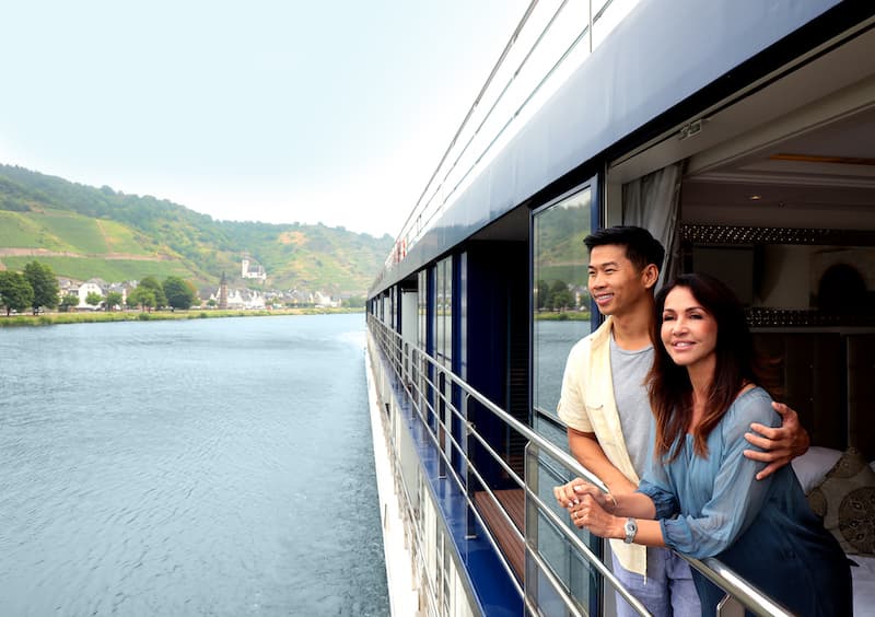 Two people standing on the balcony of their river cruise ship cabin