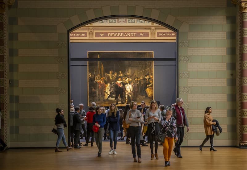 People walking around the Rijksmuseum with Rembrandt's The Night Watch in the background