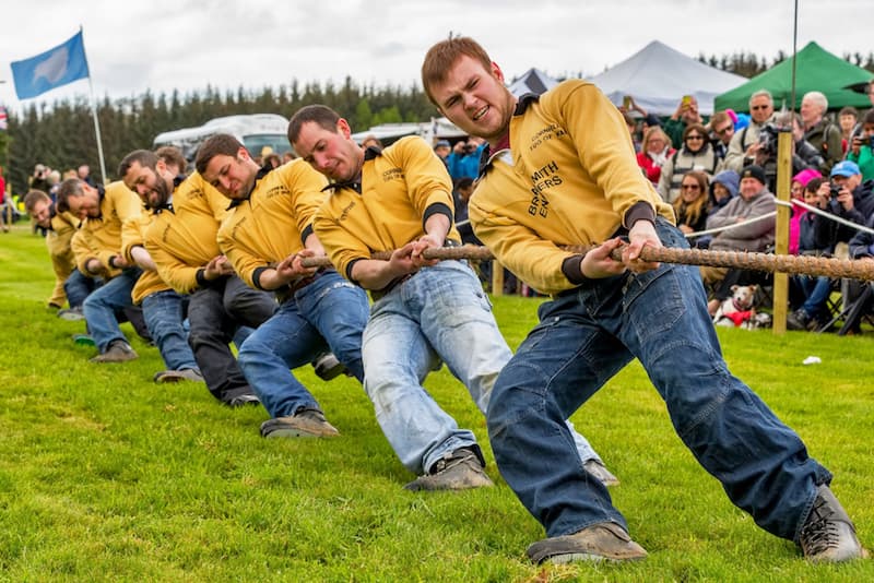 A row of guys pulling during Tug O’War at The Highland Games in Scotland