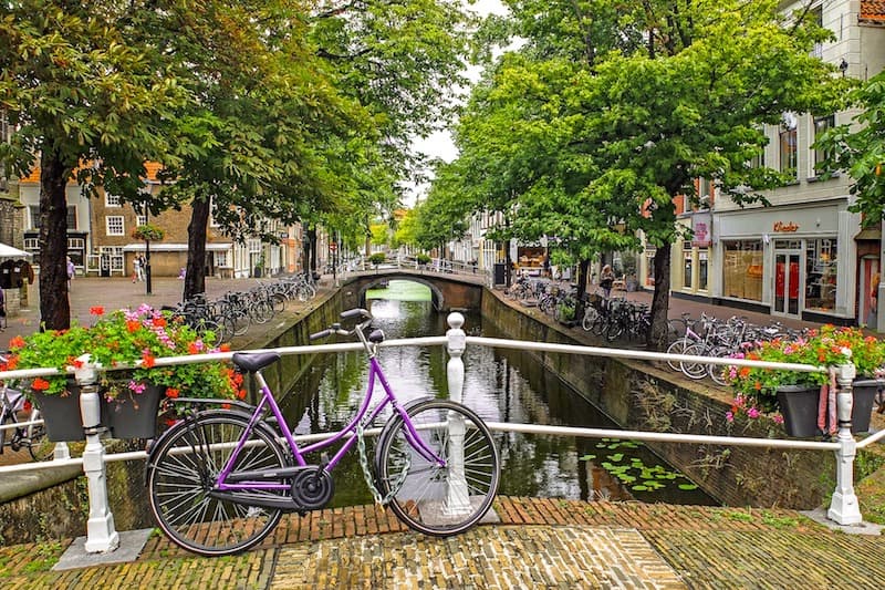 Canal bridge in the Netherlands with a bike leaning up against the railing.