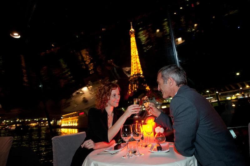 Two people toasting to Bastille Day from their Seine River Cruise boat
