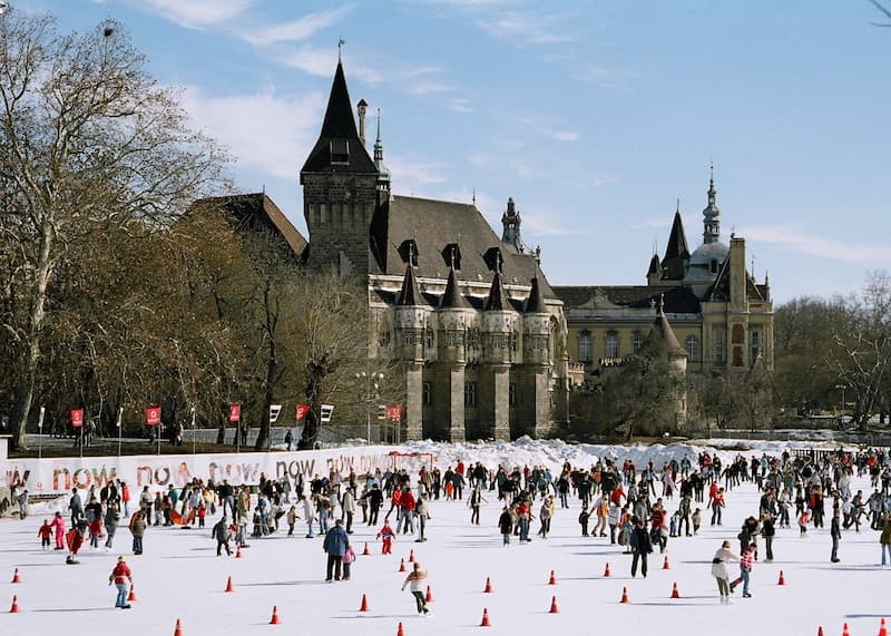People ice skating in the Budapest with a castle in the background