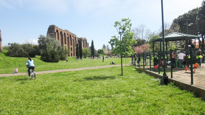 Playground and person riding a bike inside Rome's Aqueduct Park