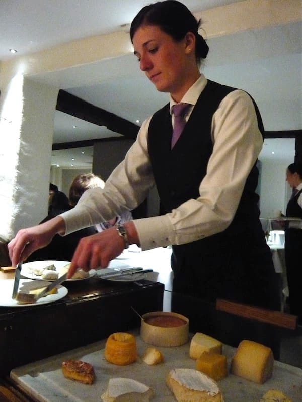 Woman serving a french cheese plate at a restaurant