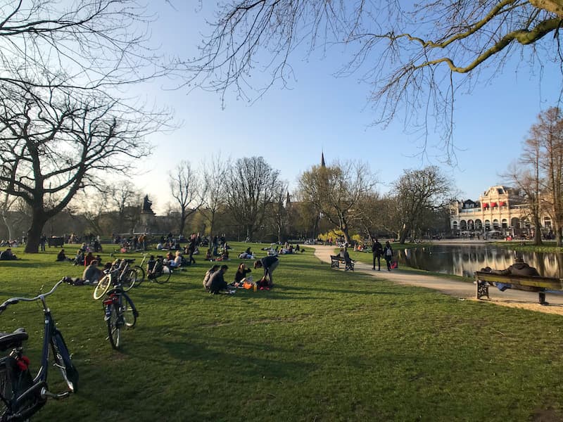 People sitting on the lawn with their bikes at Vondelpark in Amsterdam