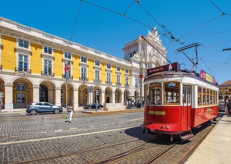 Red tram driving down a street in Lisbon, Portugal.